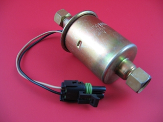 A brass-colored fuel lift pump For all GM and Chevy 6.5 diesels laying on a red background.